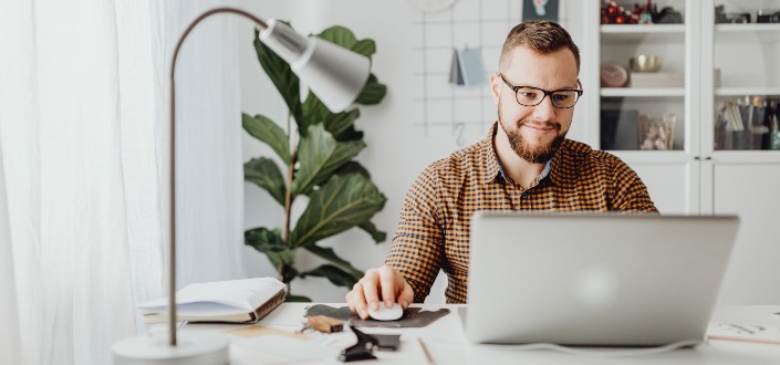 man smirking while looking at his laptop