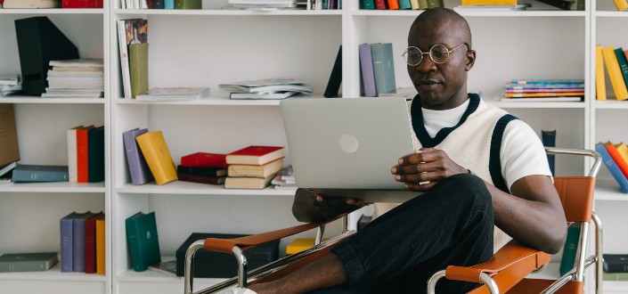 A Man Sitting on an Armchair While Using a Laptop