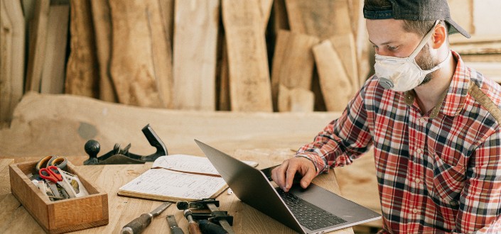 Man Using a Laptop at a Wood Workshop