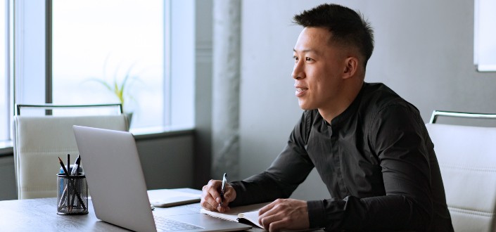 Man in Black Long Sleeve Shirt Looking at the Screen of a Laptop