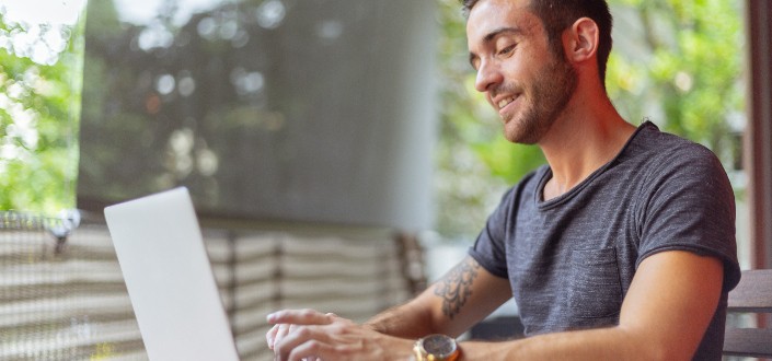 man using laptop outside a building