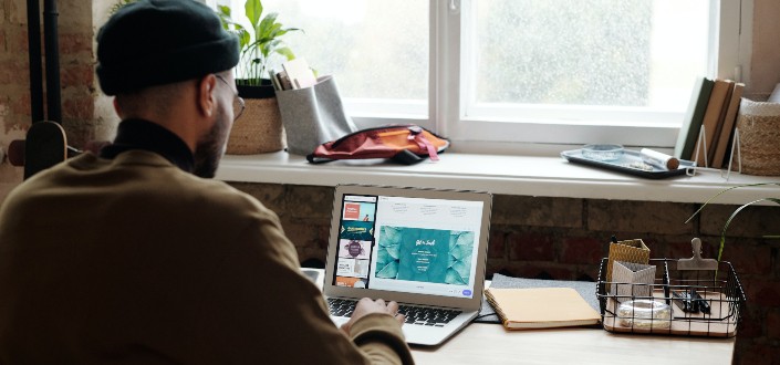 Man Using Laptop Near His Room Window