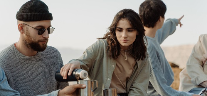 Woman Pouring a Drink to Man's Stainless Mug