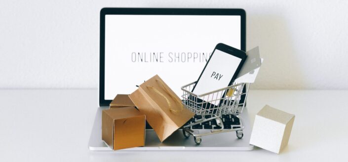 A Miniature Shopping Cart and Phone on a Laptop