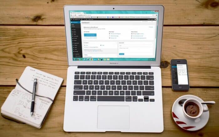 Desk With Laptop, Coffee, Phone, and Notebook - Webflow vs WordPress