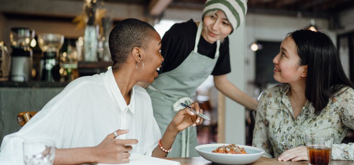 Cheerful colleagues tasting food in cafeteria