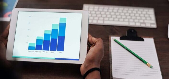 Person Holding Ipad Showing a Bar Graph