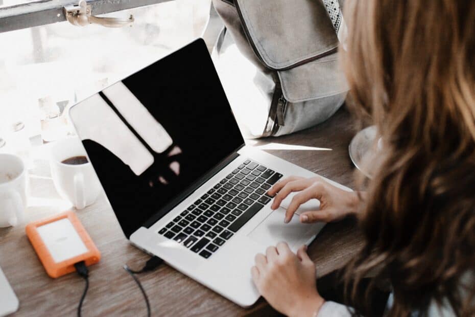 Close-up Photography of Woman Sitting Beside Table While Using Macbook