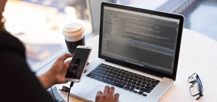 Person Holding Smartphone while using Laptop