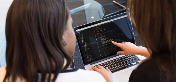 Two Women Looking at Code in Laptop
