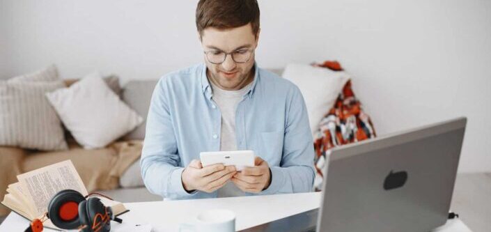 Man Sitting at Desk and Using Tablet