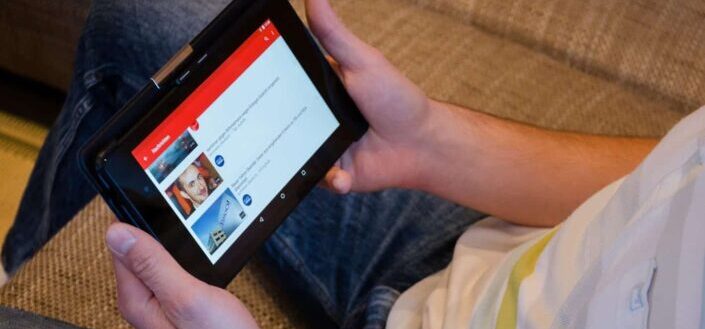 Person Holding Tablet Computer Showing Videos